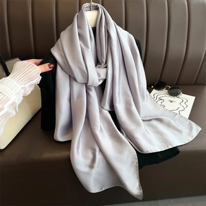 Close-up of grey satin silk scarf hanging on a hanger with stylish minimalist props