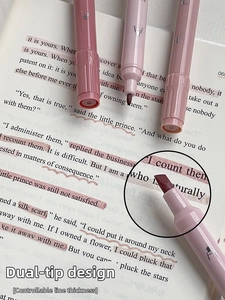 Close-up of pink dual-tip highlighter with round and chisel nibs on open book page