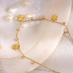 Detail view of 18K gold plated flower pendant and zircon stones on a white seashell