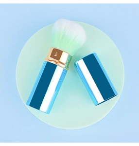 Détail du pinceau de maquillage rétractable avec manche bleu et poils dégradés verts