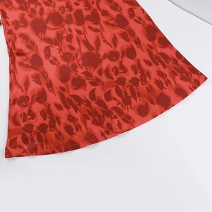 Detail view of red floral print fabric showing stitching and draped texture on the dress