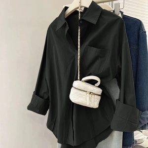 Détail d'une chemise noire à manches longues avec poche et petit sac blanc matelassé