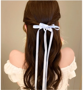 Detail view of a light blue long ribbon bow hair clip on elegant half-up hairstyle