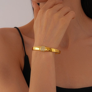 Detail eines goldenen geometrischen Armreifs mit Pavé-Kristallen am Handgelenk