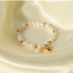Detail of freshwater pearls with gold heart pendant on a yellow silk background