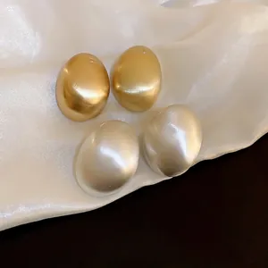 Minimalist geometric oval metal stud earrings in matte gold and pearl white finish