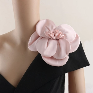 Detail of a large pink fabric rose brooch on a black dress shoulder for formal wear