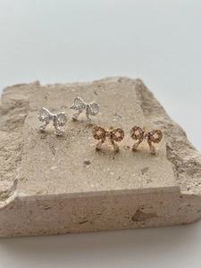 Detailed shot of luxury bow earrings in gold and silver finish with sparkling zircons