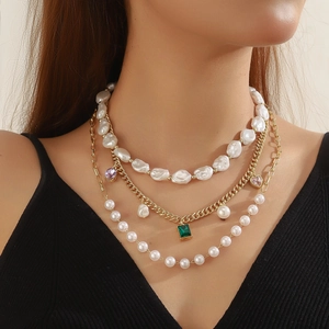 Close-up of triple-layered necklace with baroque pearls and colorful gemstone pendants