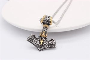 Detail of silver and gold Viking Thor's Hammer pendant with vintage brushed metal texture