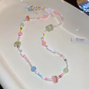 Gros plan d'un collier choker avec perles pastel colorées disposé sur céramique