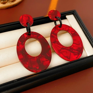 Detailaufnahme roter ovaler Harzohrringe mit Textur auf einem Schmuckdisplay