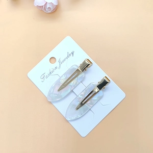 Close-up of pearl white acetate hair clips with gold metal base on display card