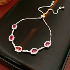 Detaillierte Makroansicht von fünf ovalen roten Zirkonia mit Halo-Fassung auf Silberarmband