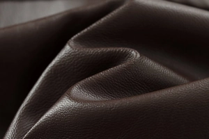 Macro shot of dark brown faux leather material with pebble grain and matte finish texture