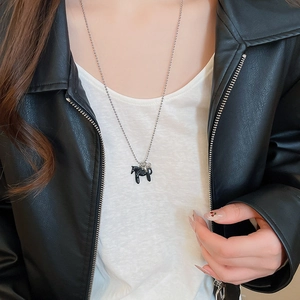 Détail d'un collier avec pendentif cheval porté par un mannequin en veste de cuir