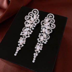 Detailed macro view of silver bow tassel earrings with sparkling rhinestones on red silk