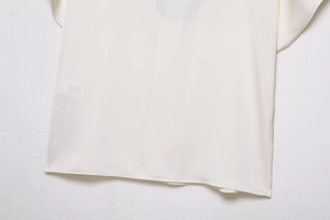 Detailansicht des weißen Satin-Oberteils mit hochwertiger Nahtführung und feiner Textur