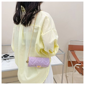 Detail of lavender quilted cylinder bag featuring a gold chain strap and turn-lock