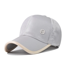 Detail of light gray satin baseball cap with M badge and beige brim edge contrast