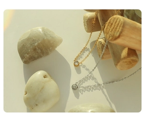 Close-up of minimalist gold and silver zircon pendant necklaces on natural wood background