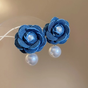 Macro shot of denim rose earrings with central pearl and hanging white pearl pendant