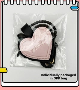Pink leather heart keychain with black spiral strap in individual OPP bag packaging
