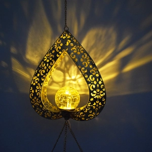 Detailed view of solar heart wind chime showing bronze hollow pattern and cracked glass ball