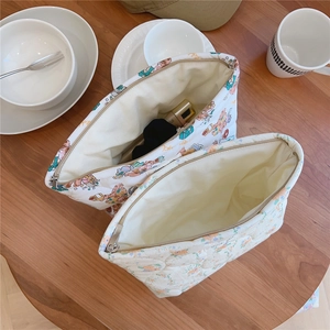 Detailed view of quilted cotton makeup bags with floral and bear prints on wooden table