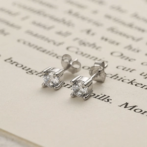 Classic S925 sterling silver four-prong round zircon stud earrings on book page