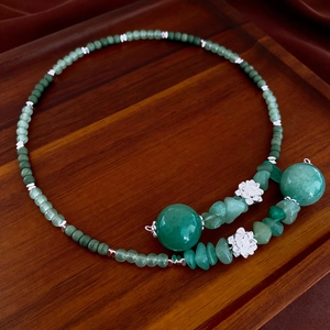 Detail of beaded jade lotus necklace with green stones and silver floral charms