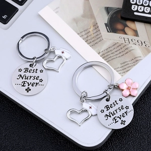 Two Best Nurse Ever stainless steel keychains with charms on a white laptop keyboard
