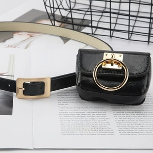 Minimalist black leather belt with mini pouch and gold buckle on a stylish magazine background