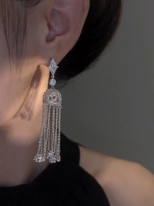 Close-up of elegant silver tassel earrings with geometric diamond-encrusted drops on model