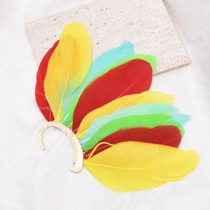 Detailed close-up of vintage multi-colored peacock feather ear cuff with golden metallic hook