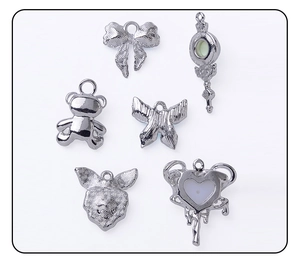 Macro detail of assorted silver alloy charms featuring hearts bows and magic wands for DIY