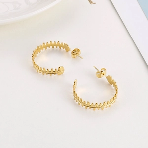 Detailed macro view of golden fishbone-shaped C-style earrings in polished titanium steel