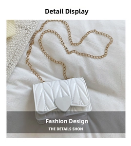 Detail of white quilted crossbody bag with heart buckle and gold chain strap