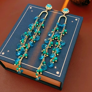 Detail of bohemian gold tassel earrings with blue stones and green turquoise beads