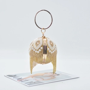 Detail of golden spherical evening bag with pearl feathers and fringe hanging