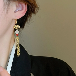 Macro side view of elegant gold tassel earrings with cloud pattern on a model