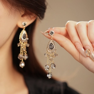 Detail of vintage bohemian teardrop earrings with gold fringe tassels and rhinestones