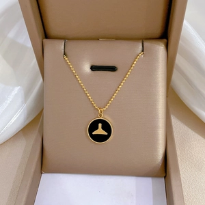 Macro detail of golden mermaid tail necklace with black circular charm in jewelry box