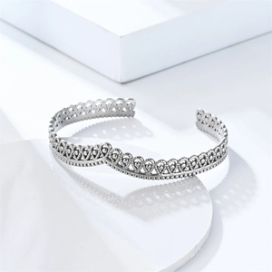 Elegant silver crown hollow lace cuff bracelet in stainless steel on white pedestal