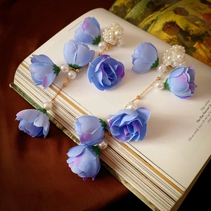 Eleganti orecchini lunghi con frange, fiori in pizzo blu e perle su un libro d'epoca