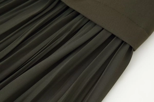 Detailed view of dark olive green pleated midi dress fabric with fine accordion folds