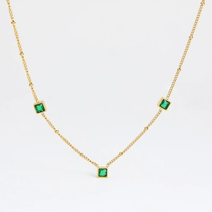 Détail du collier en chaîne dorée avec trois zircons verts de forme carrée