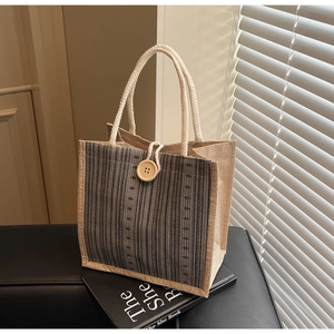 Close-up of linen tote bag with striped pattern, wooden button, and cotton rope handles