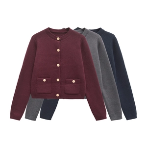 Detailed view of knit cardigans in burgundy, grey, and navy with gold button accents