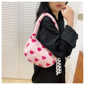 Detail of pink plush faux fur shoulder bag featuring all-over dark pink heart patterns